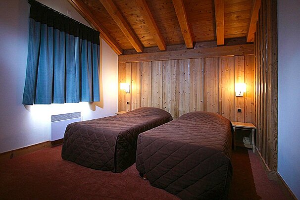 A bedroom with two beds and a wooden ceiling