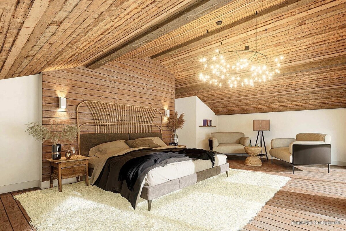 Rustic attic bedroom with wood-paneled walls and ceiling, a bed with a rattan headboard, a fluffy rug, and a sparkling chandelier.