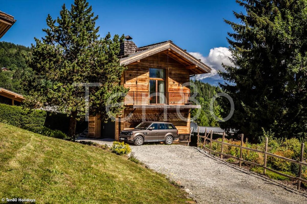 A range rover is parked in front of a wooden house