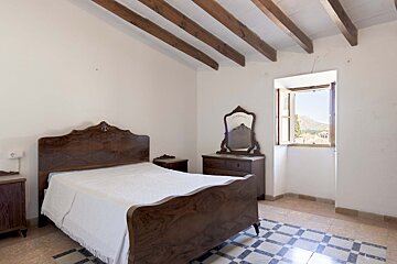 A bedroom with a wooden bed and a mirror