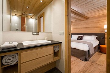 A bathroom with a sink and a mirror next to a bed