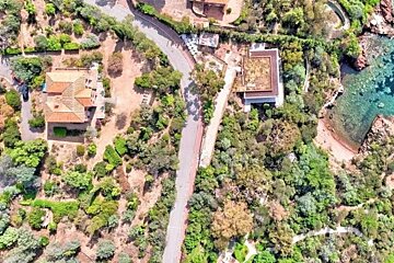 An aerial view of a house surrounded by trees and a road