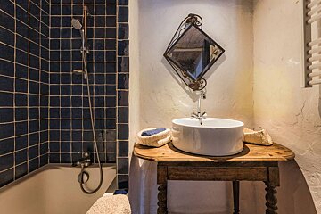 A bathroom with blue tiles and a sink on a wooden table