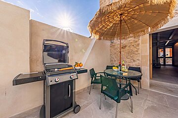 A patio with a table and chairs and a grill