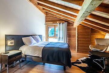 A bedroom with a bed and a chair in it