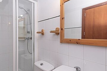 A bathroom with a toilet a shower and a mirror