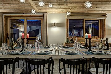 A dining room table with plates and candles on it