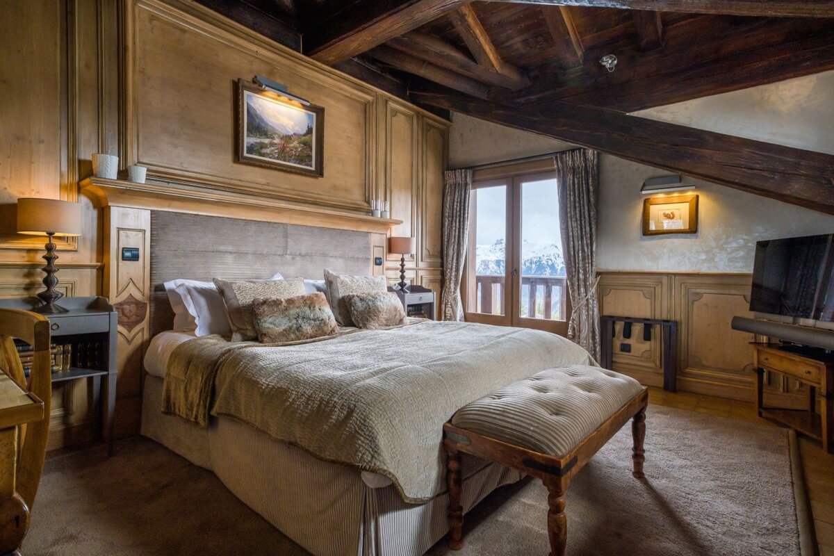 A bedroom with a large bed and a bench