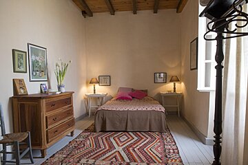 A bedroom with a dresser and a bed with a rug on the floor