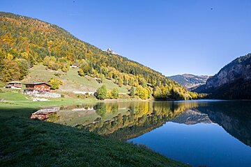 A house sits on the shore of a lake surrounded by mountains