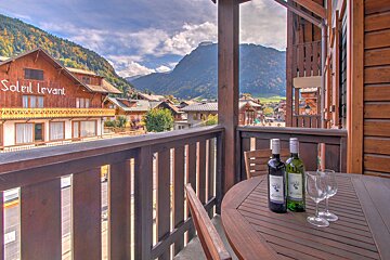 Two bottles of wine sit on a table in front of soleil levant