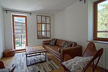 A living room with a couch and chairs and a hotel sign on the window