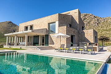 A large stone house with a swimming pool in front of it