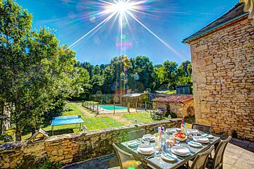 A patio with a table and chairs and a pool in the background