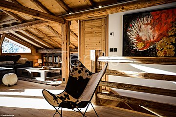 A living room with a cowhide chair and a painting on the wall