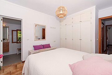 A bedroom with a white bed and purple pillows