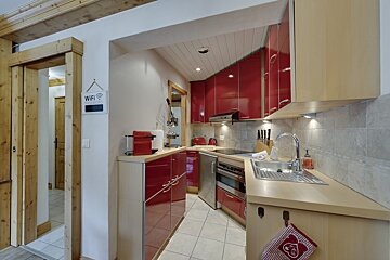 A kitchen with red cabinets and a nespresso machine