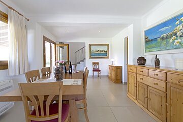 A dining room with a table and chairs and a painting on the wall
