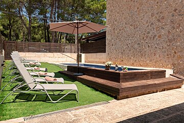 A row of lounge chairs are lined up in front of a swimming pool
