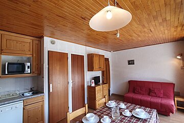 A kitchen with a red couch and a table with cups and saucers on it