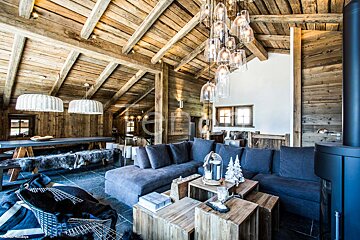 A living room with a large sectional couch and wooden tables