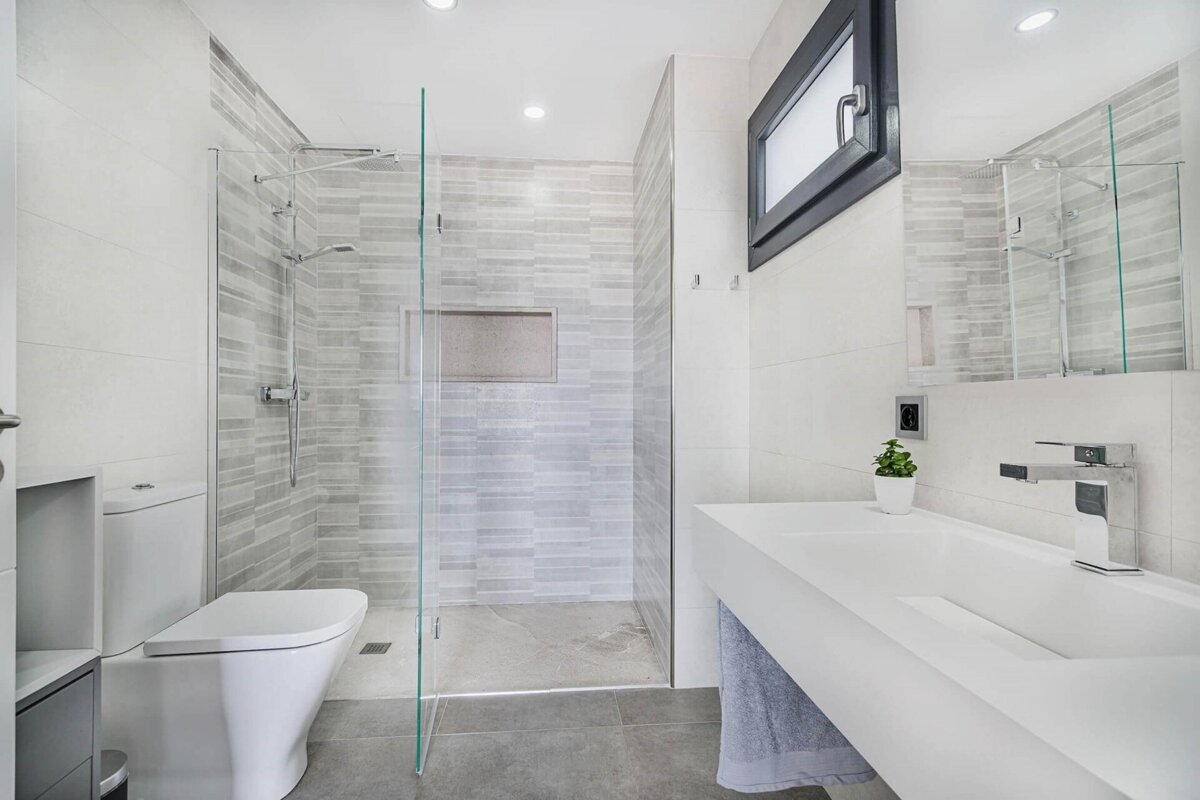 A bathroom with a toilet a sink and a walk in shower
