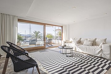 A living room with a white couch and a black and white rug