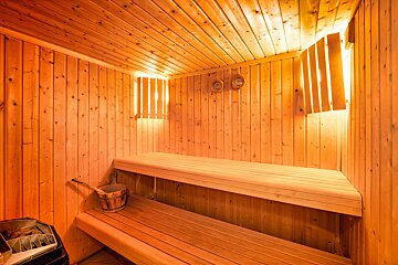A wooden sauna with a bucket on the bench