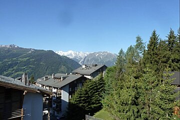 A view of a mountain range with a few buildings in the foreground