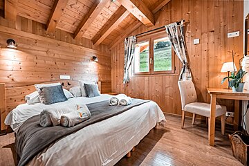 A wooden bedroom with a bed and a desk