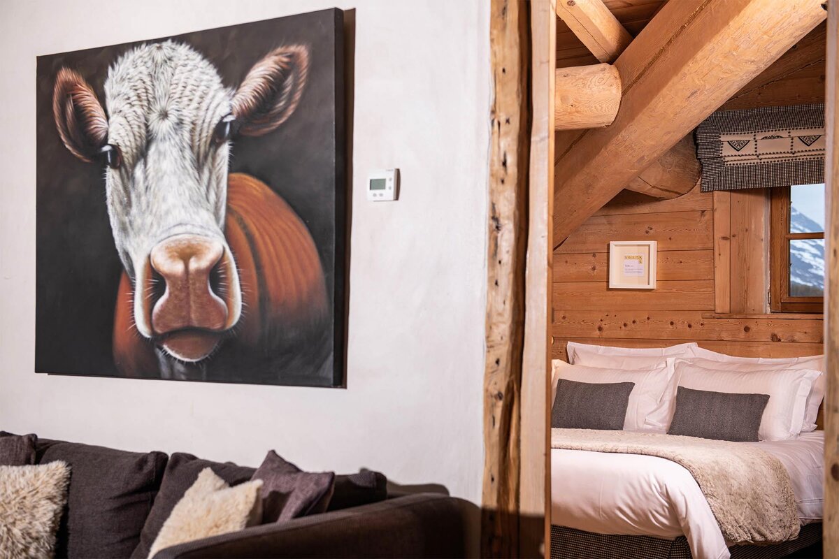 A painting of a cow on a wall next to a bed