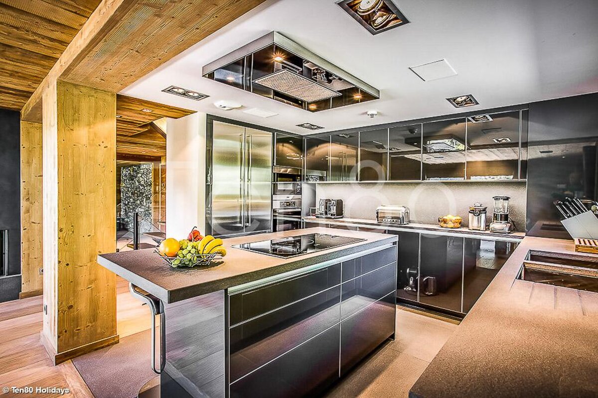 A kitchen with stainless steel appliances and a bowl of fruit on the counter