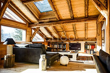 A living room with a couch and a television and a skylight above it
