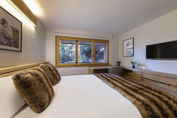 A bedroom with a large bed and a flat screen tv