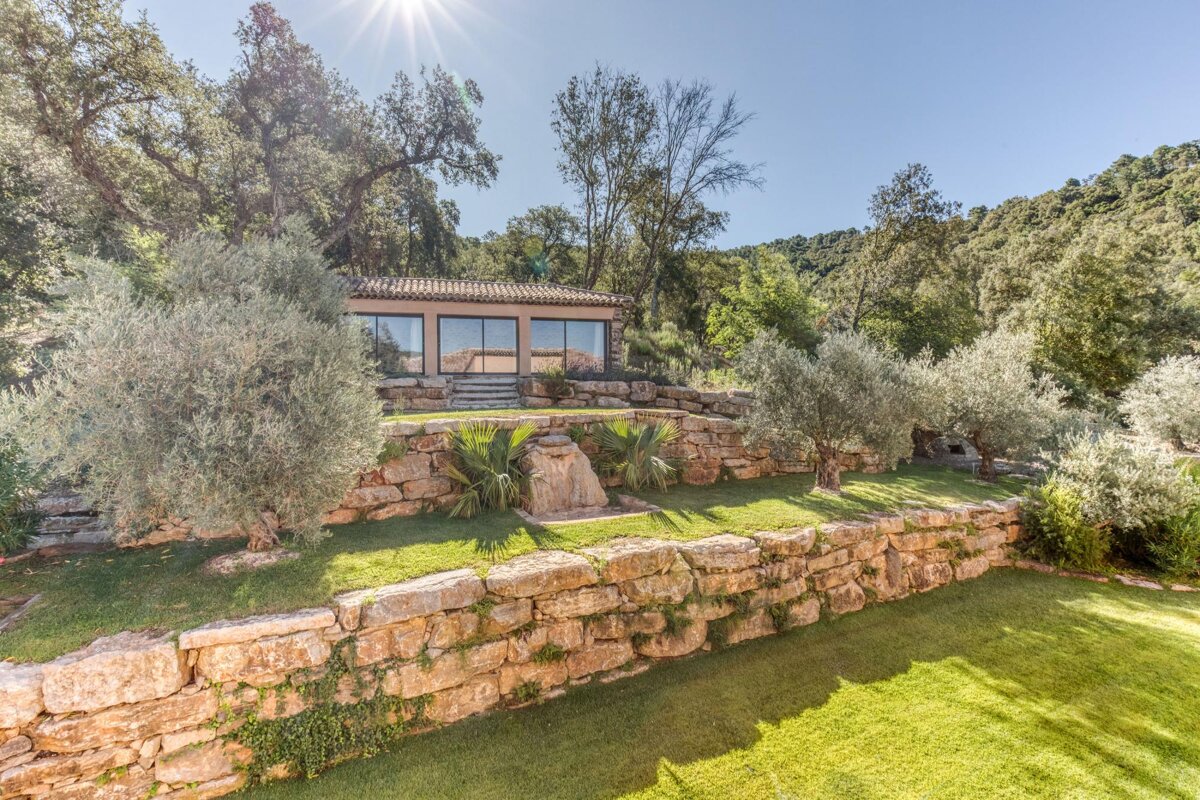A stone wall surrounds a house in the woods