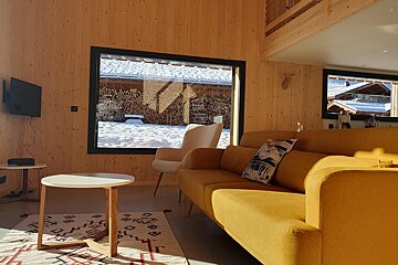 A living room with a yellow couch and a white chair