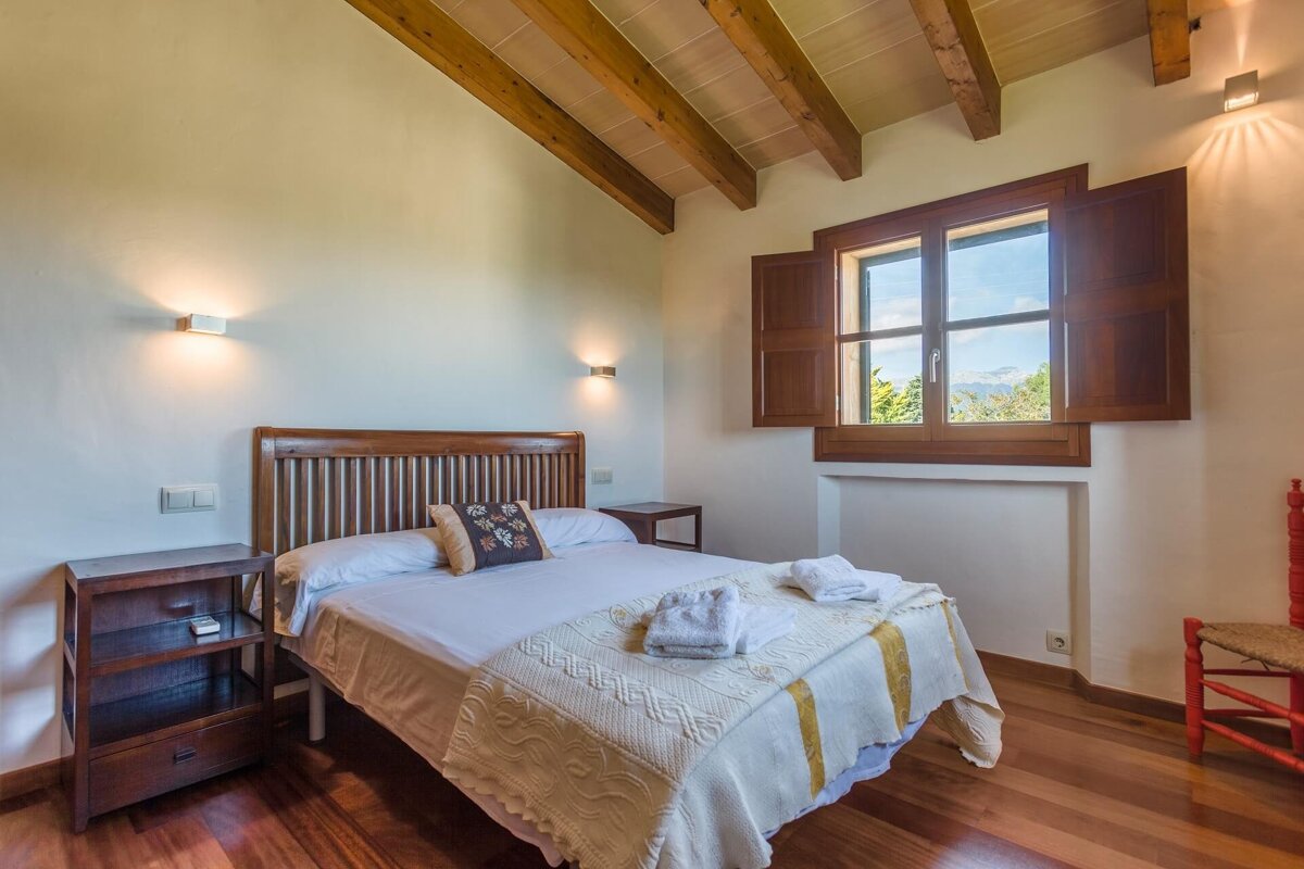 A bedroom with a bed and a window with wooden shutters