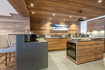 A kitchen with wooden cabinets and a tv on the wall