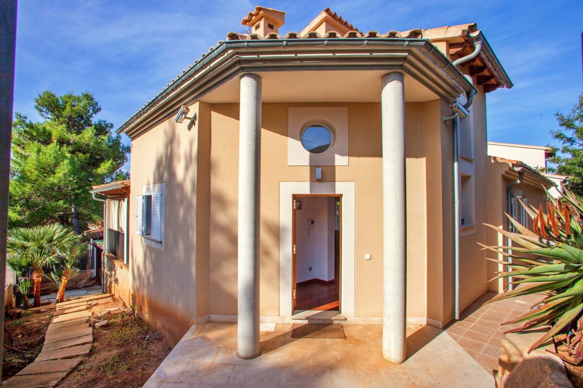 A small house with columns and a round window
