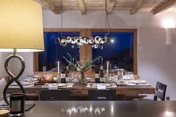 A dining room table with a lamp and a vase of flowers on it