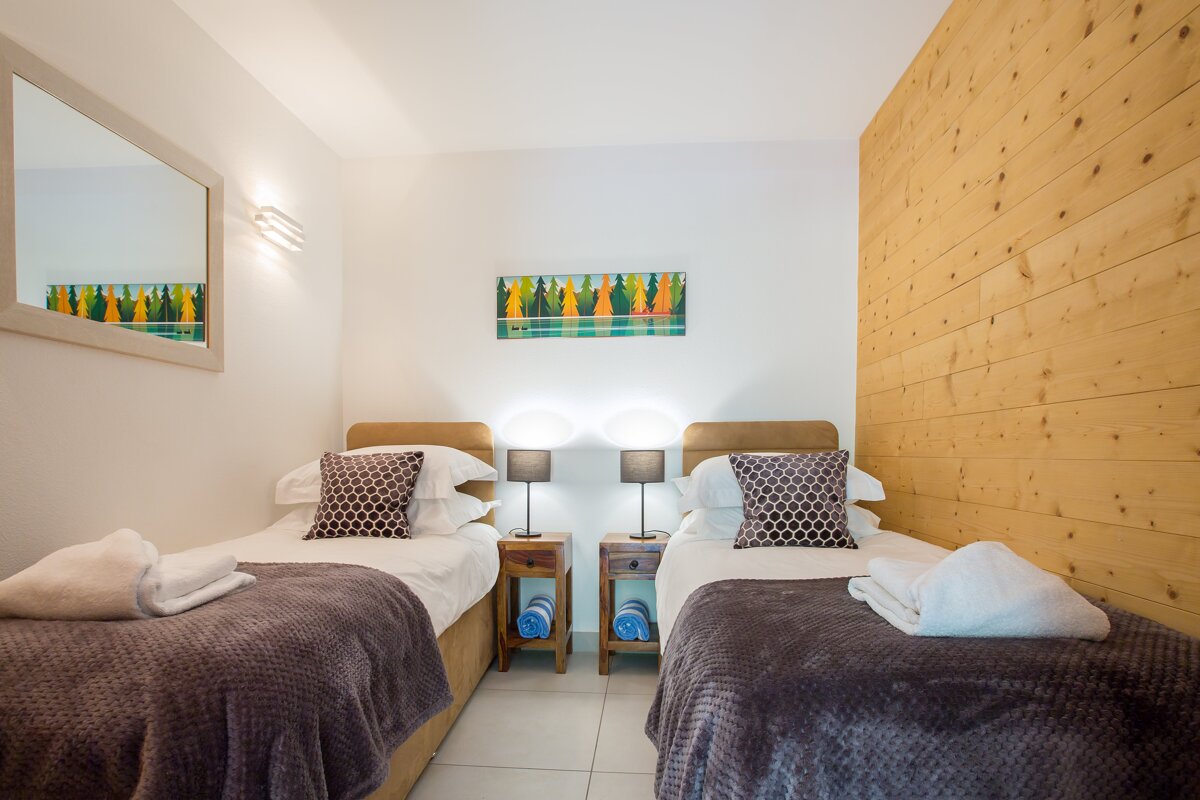 A bedroom with two beds and a painting on the wall