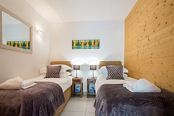 A bedroom with two beds and a painting on the wall
