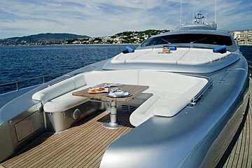A silver yacht with a wooden table on the deck
