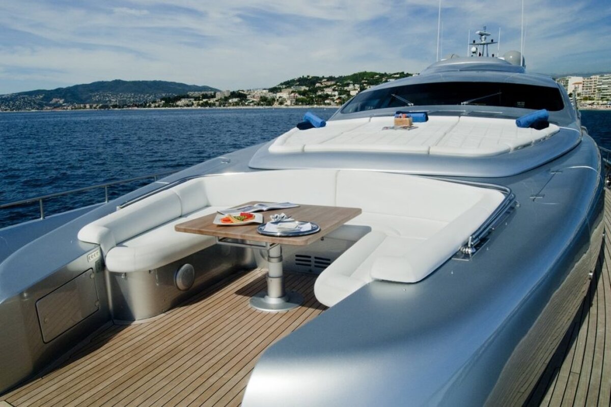 A silver yacht with a wooden table on the deck