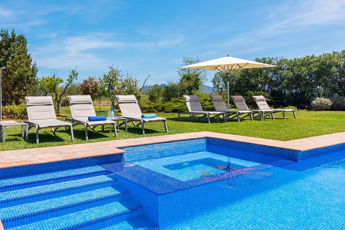 A swimming pool surrounded by lawn chairs and an umbrella