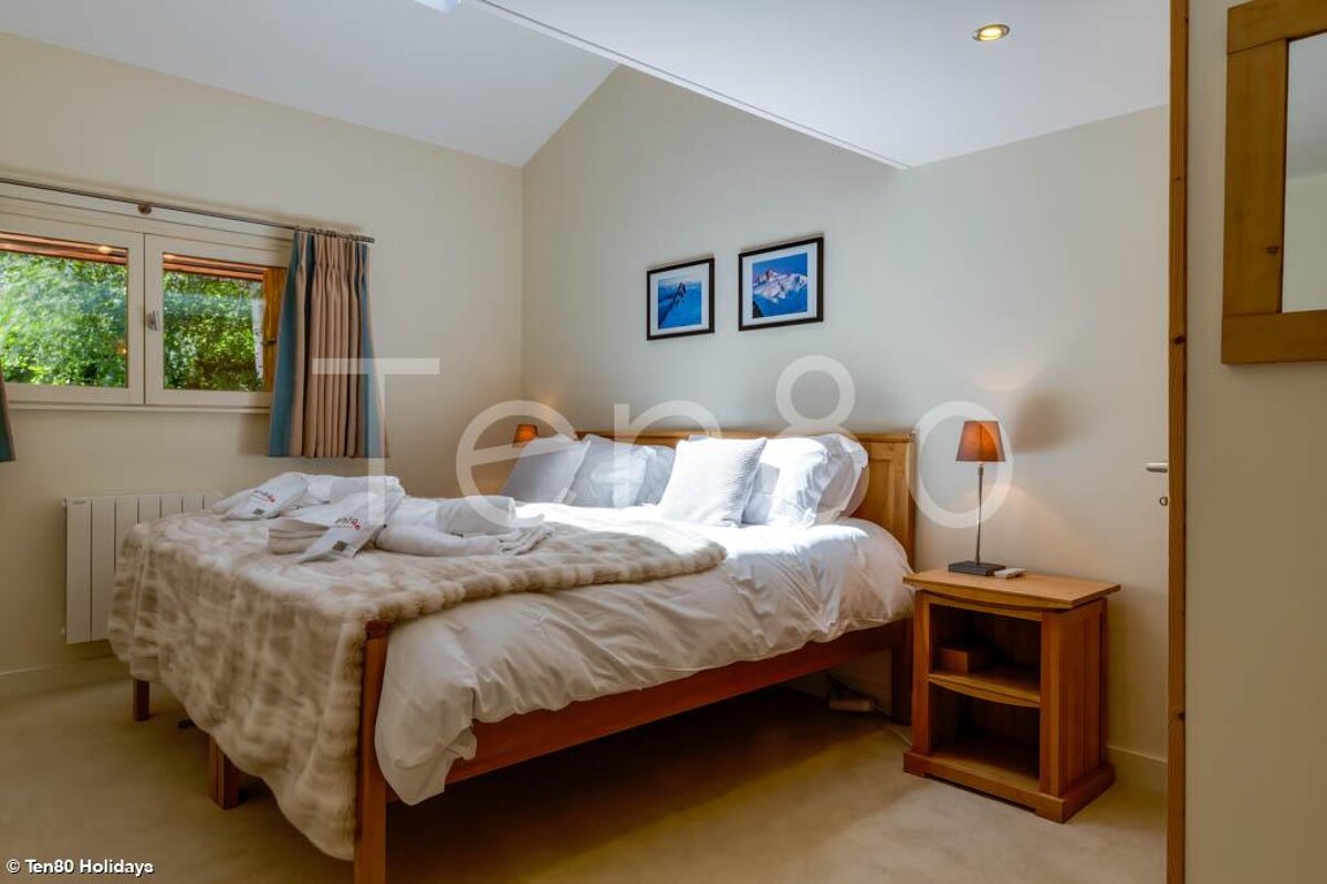 A bedroom with a bed and a nightstand and a sign that says ten80 holidays