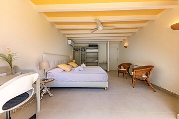 A bedroom with a large bed and a ceiling fan