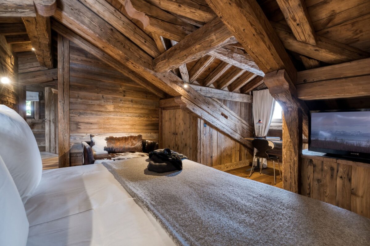 A wooden room with a bed and a television