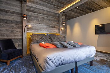 A bedroom with a large bed and a chair