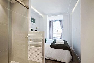 A bedroom with a bed and a towel rack